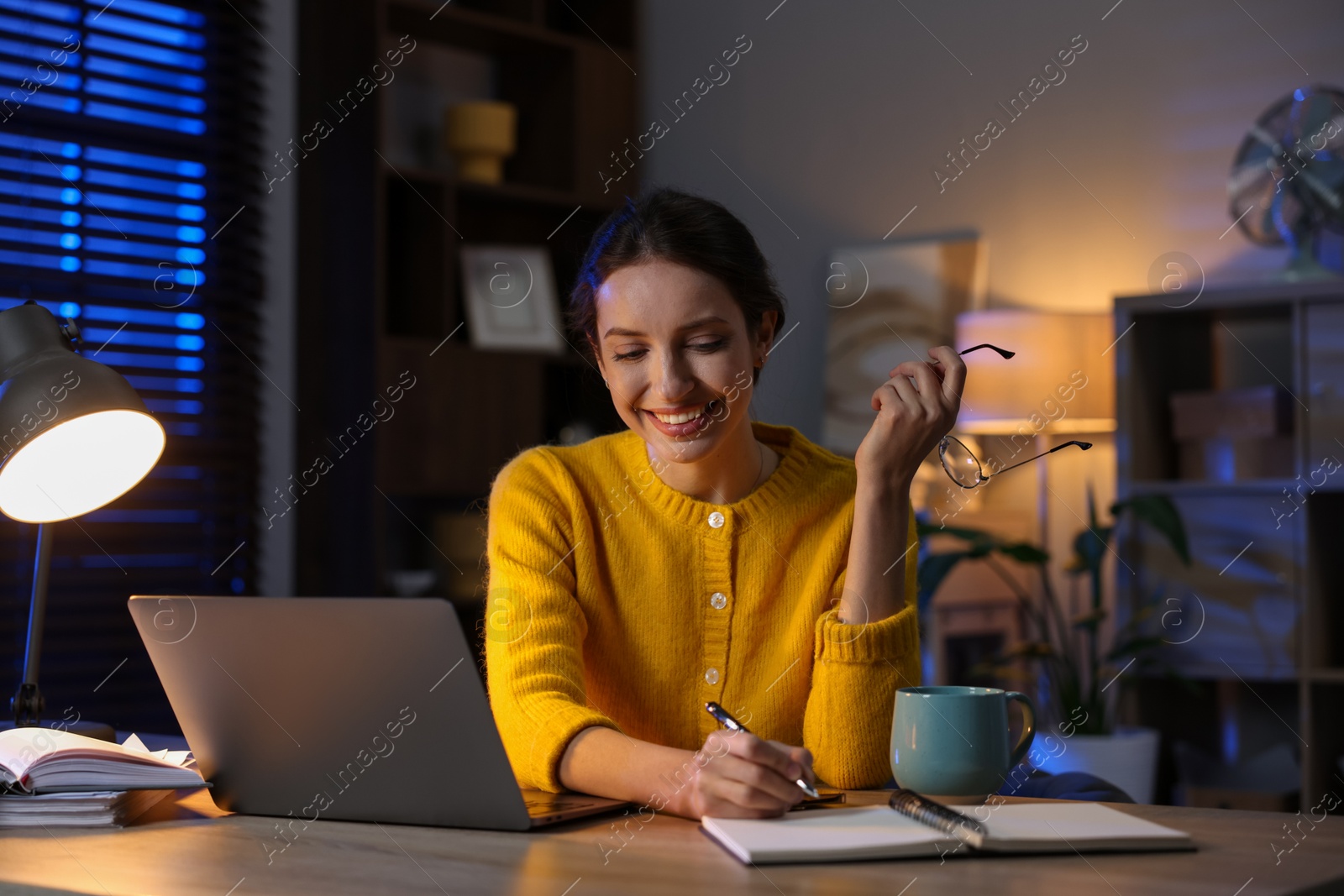 Photo of Woman taking notes while working at desk in home office