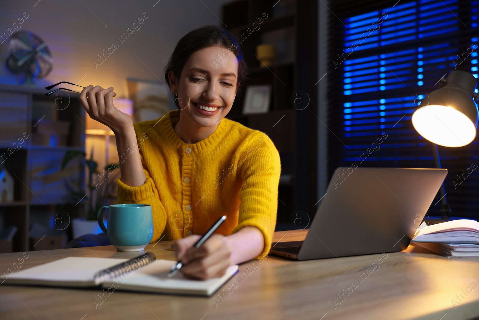 Photo of Woman taking notes while working at desk in home office