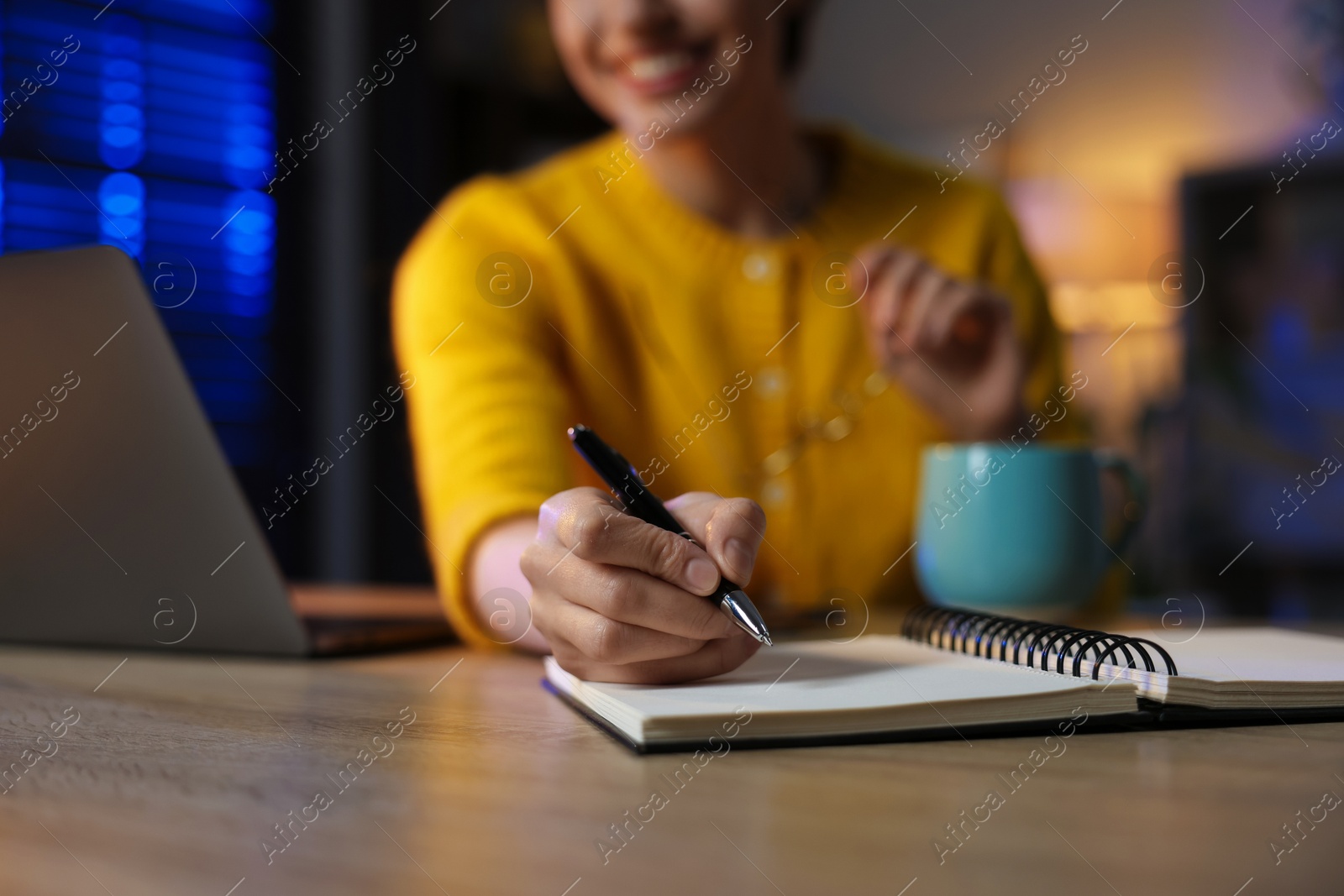 Photo of Woman taking notes while working at desk in home office, closeup