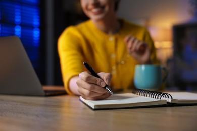 Photo of Woman taking notes while working at desk in home office, closeup