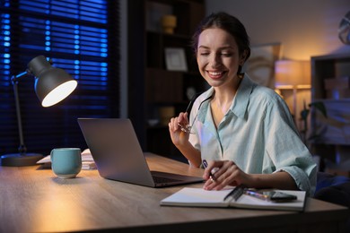 Photo of Woman taking notes while working at desk in home office