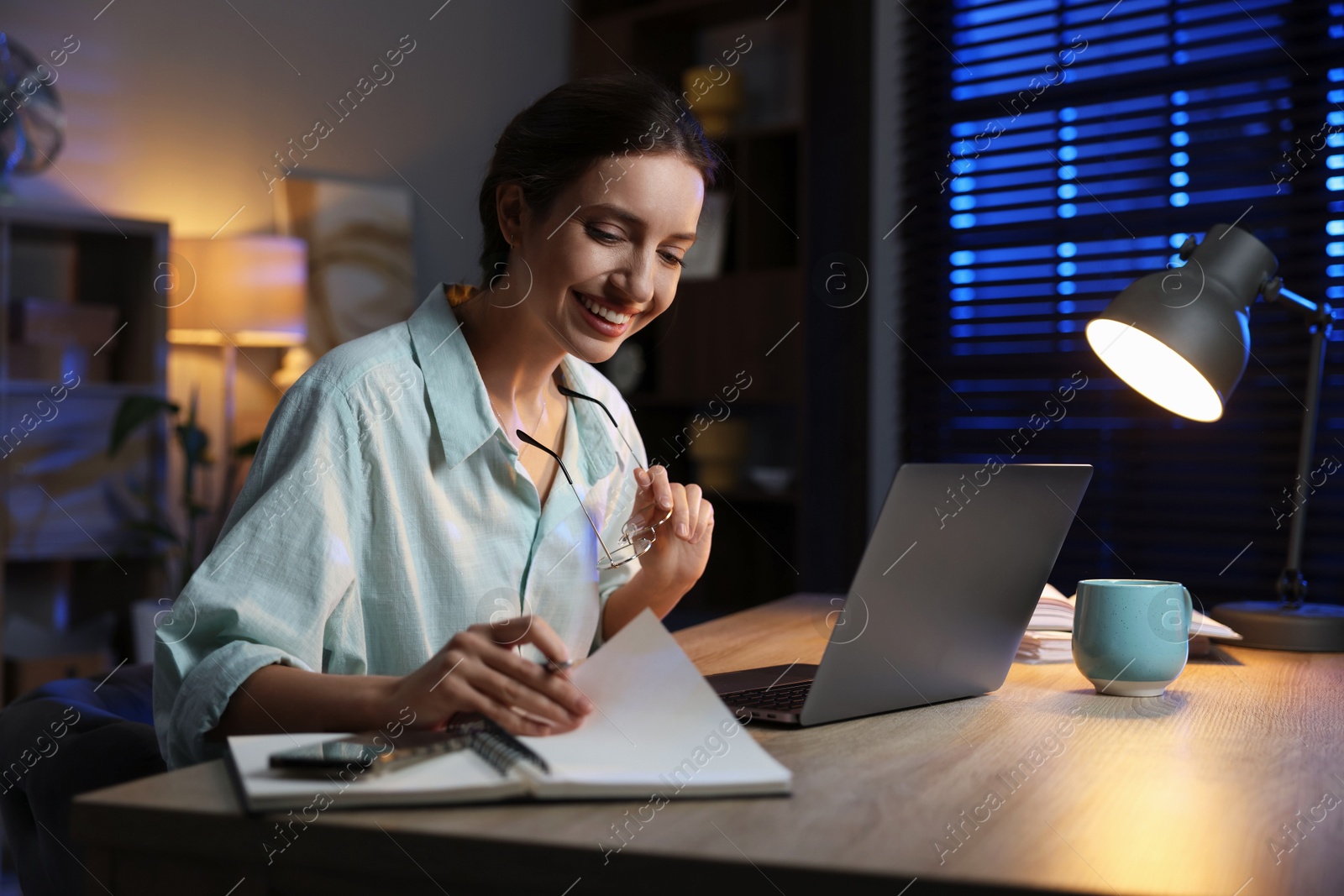 Photo of Woman taking notes while working at desk in home office