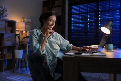 Woman working on laptop at desk in home office