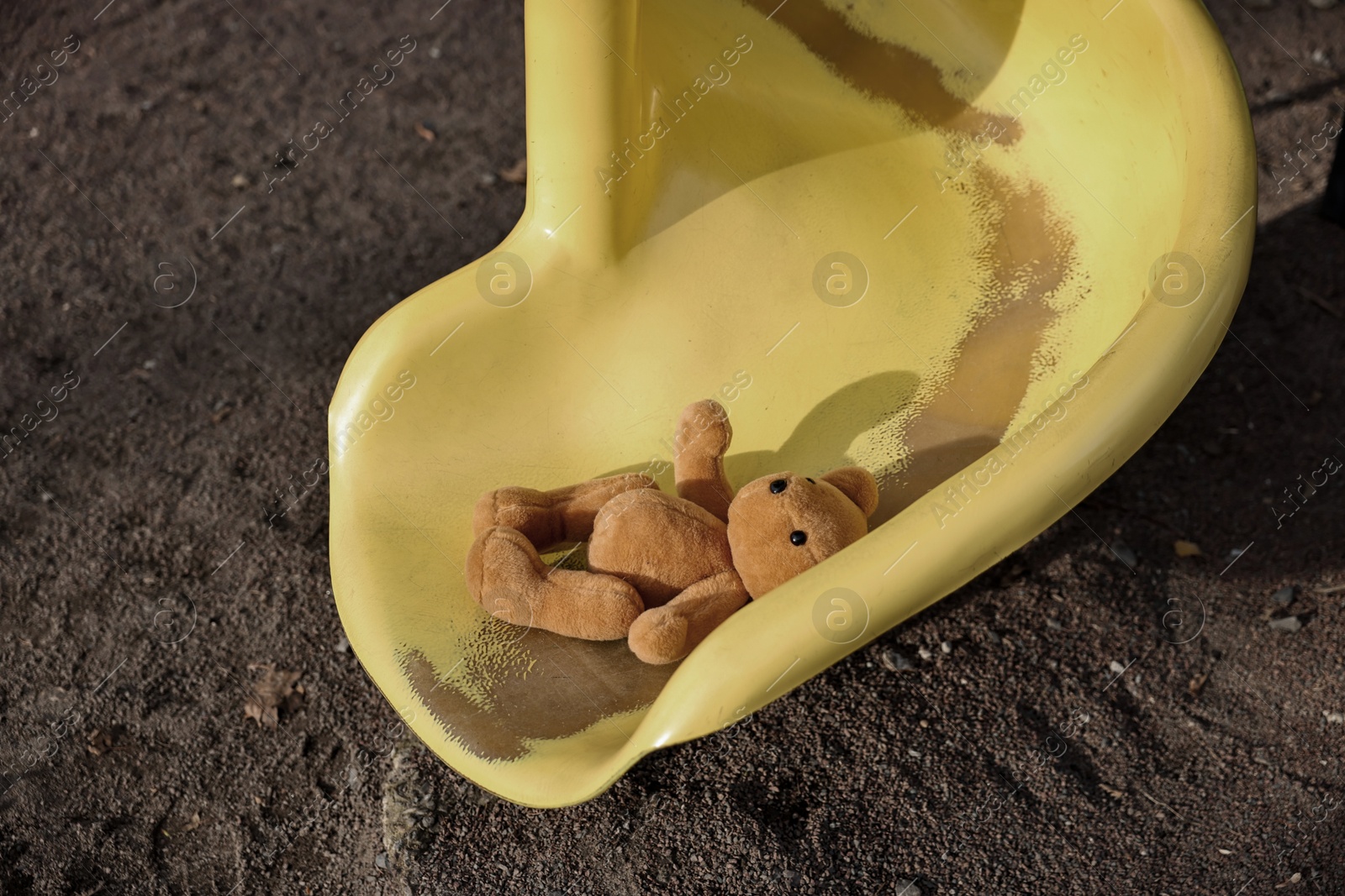 Photo of Lost brown teddy bear on slide outdoors