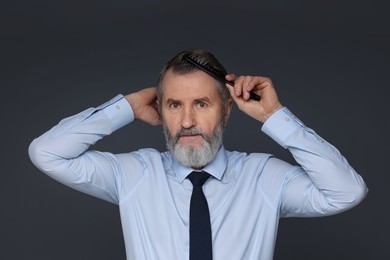 Photo of Handsome man combing his hair on dark grey background