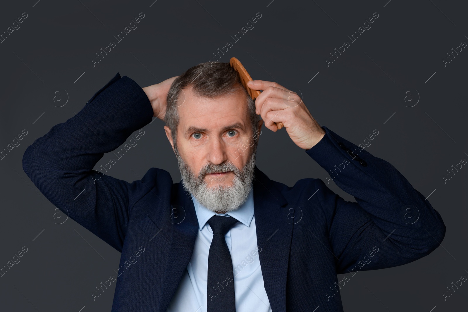 Photo of Handsome man combing his hair on dark grey background