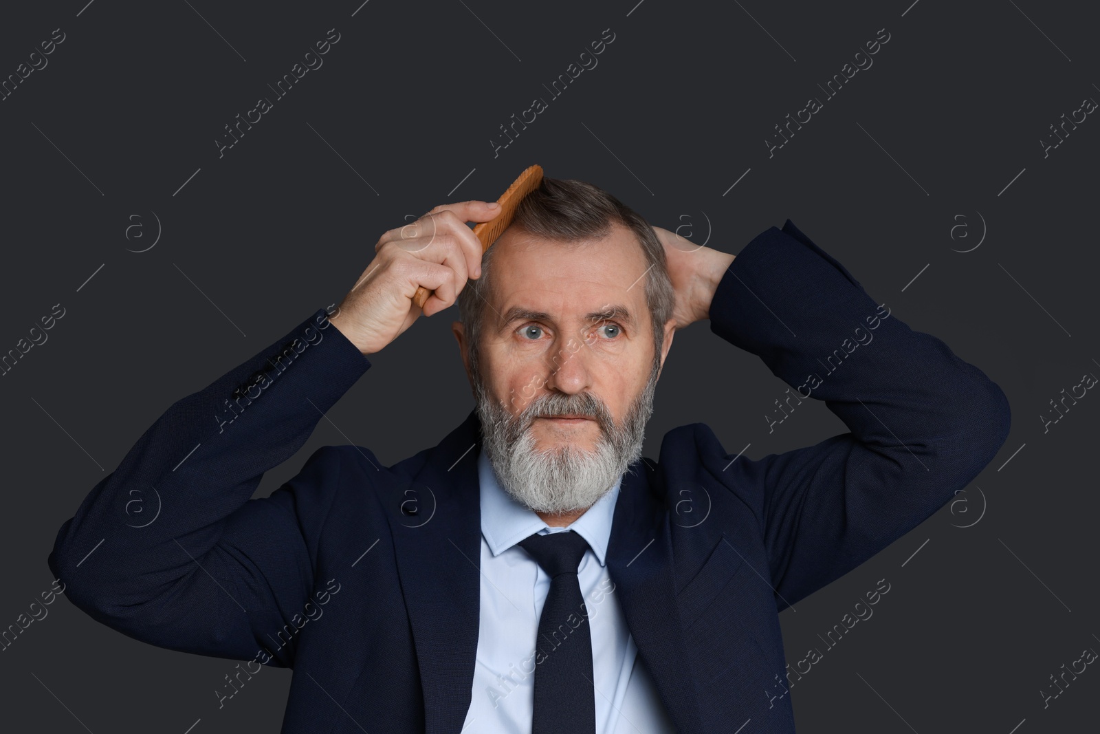 Photo of Handsome man combing his hair on dark grey background