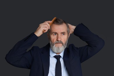 Photo of Handsome man combing his hair on dark grey background