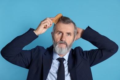 Photo of Handsome man combing his hair on light blue background