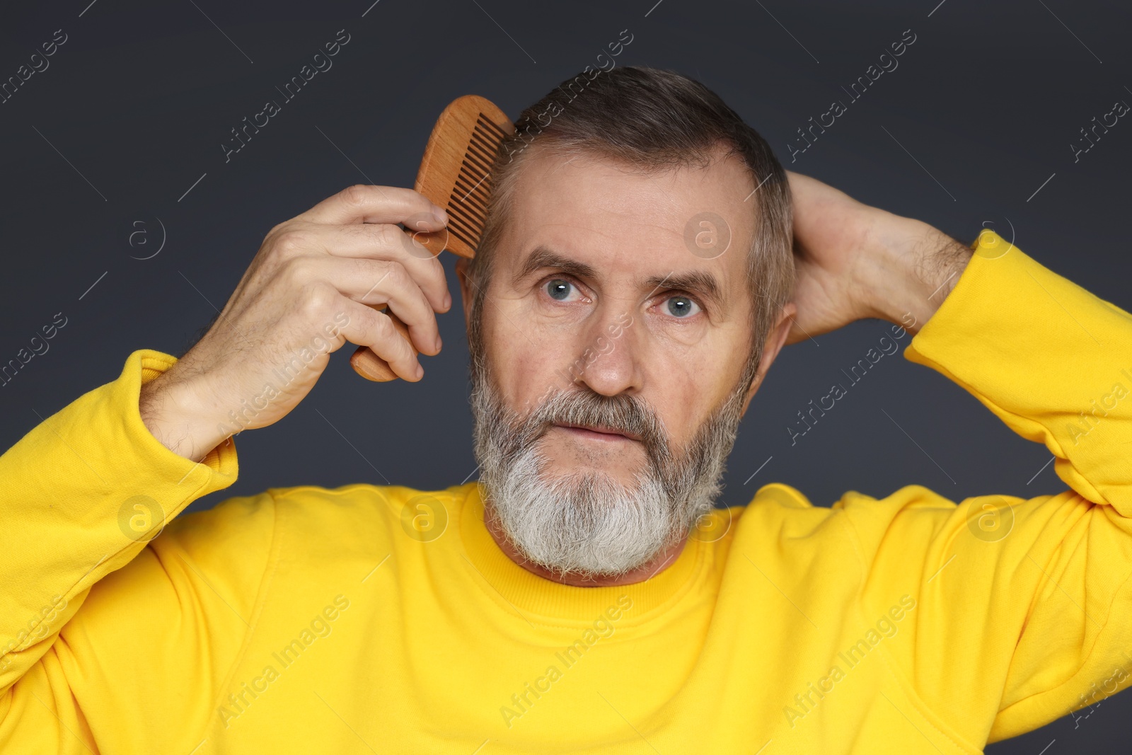 Photo of Handsome man combing his hair on dark grey background