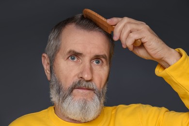 Photo of Handsome man combing his hair on dark grey background