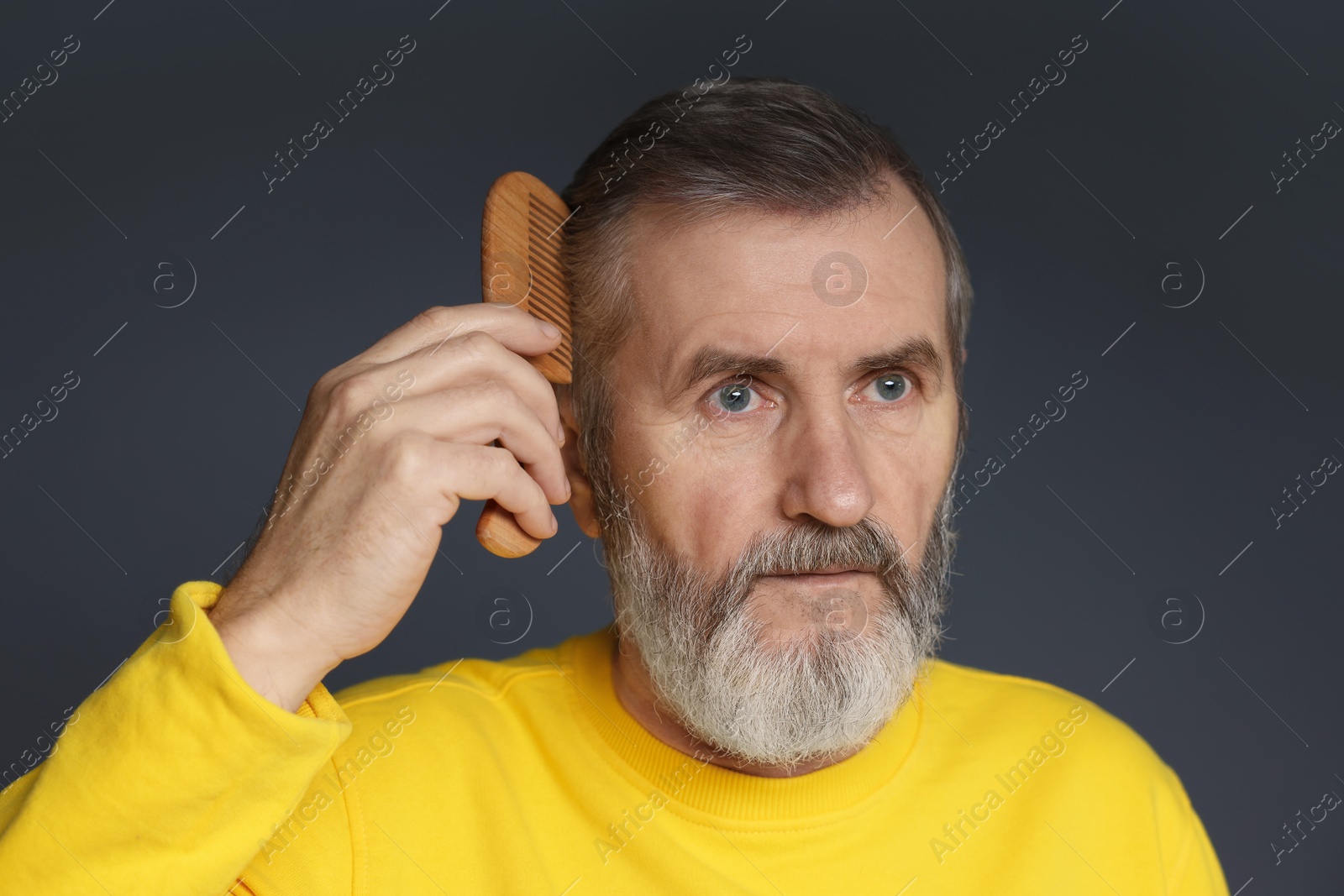 Photo of Handsome man combing his hair on dark grey background