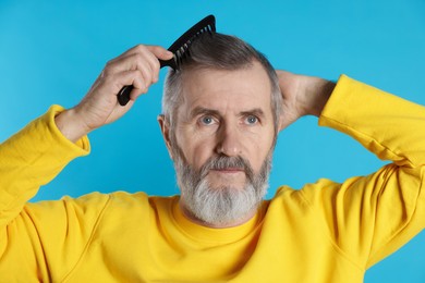 Photo of Handsome man combing his hair on light blue background