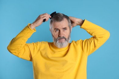 Photo of Handsome man combing his hair on light blue background