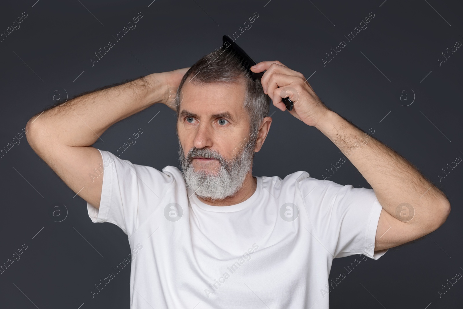 Photo of Handsome man combing his hair on dark grey background