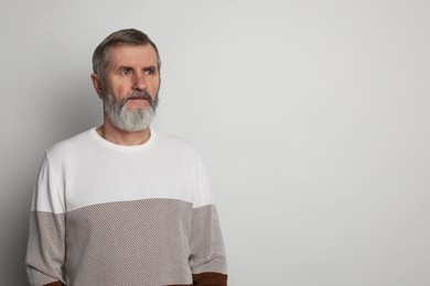 Photo of Portrait of mature man on light grey background, space for text