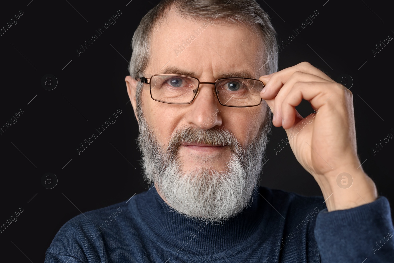 Photo of Portrait of mature man in glasses on black background