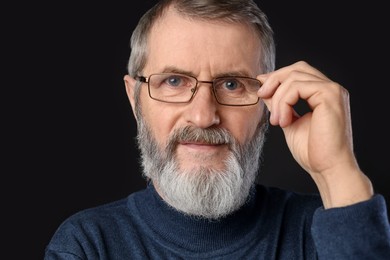 Photo of Portrait of mature man in glasses on black background