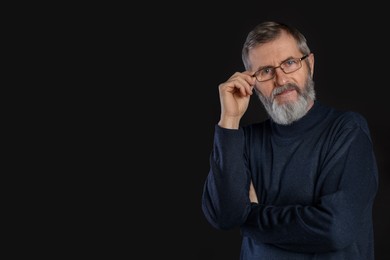 Photo of Portrait of mature man in glasses on black background, space for text