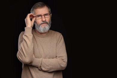 Photo of Portrait of mature man in glasses on black background, space for text