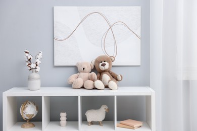 Photo of Teddy bears and decor on shelving unit in room