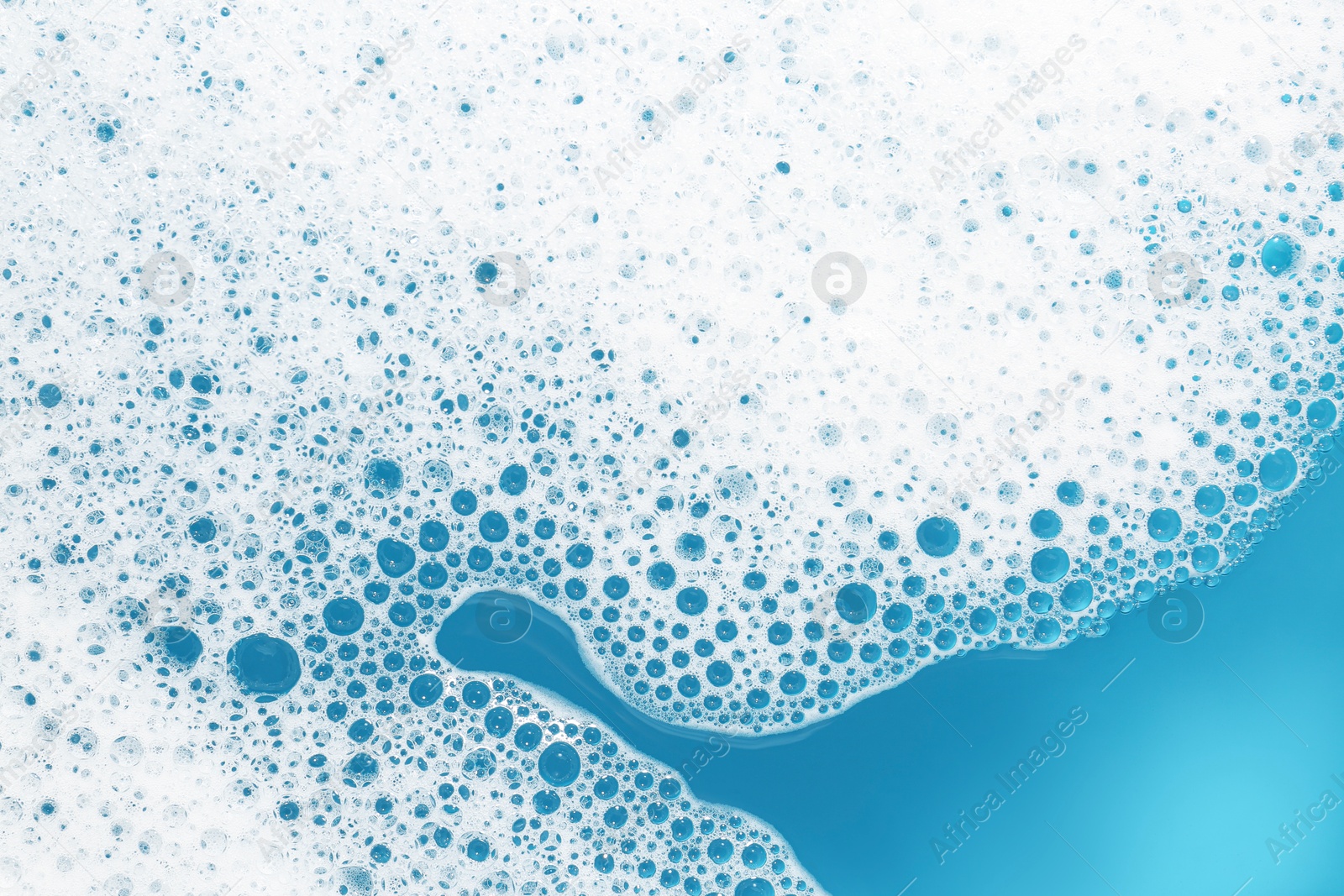 Photo of Detergent foam with bubbles on light blue background, top view