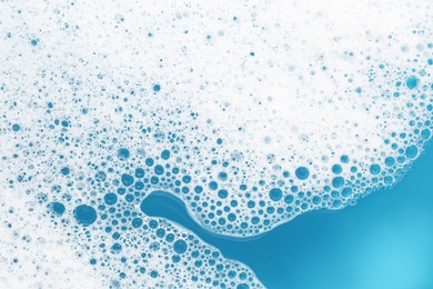 Photo of Detergent foam with bubbles on light blue background, top view