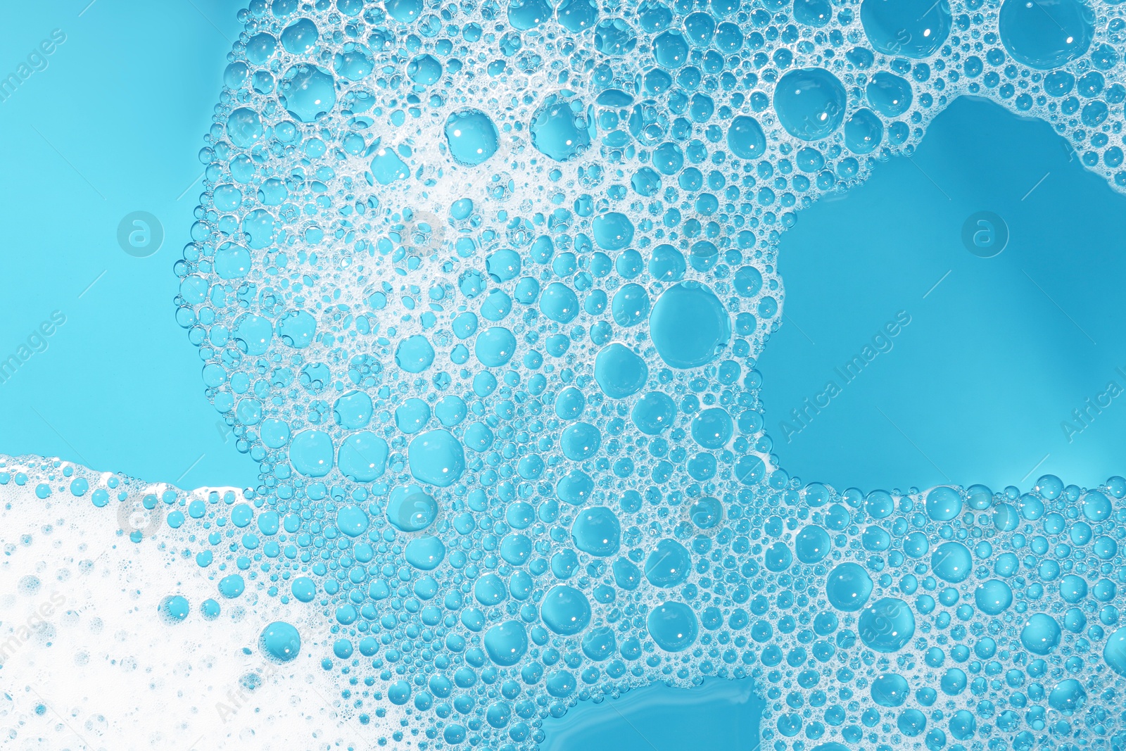 Photo of Detergent foam with bubbles on light blue background, top view