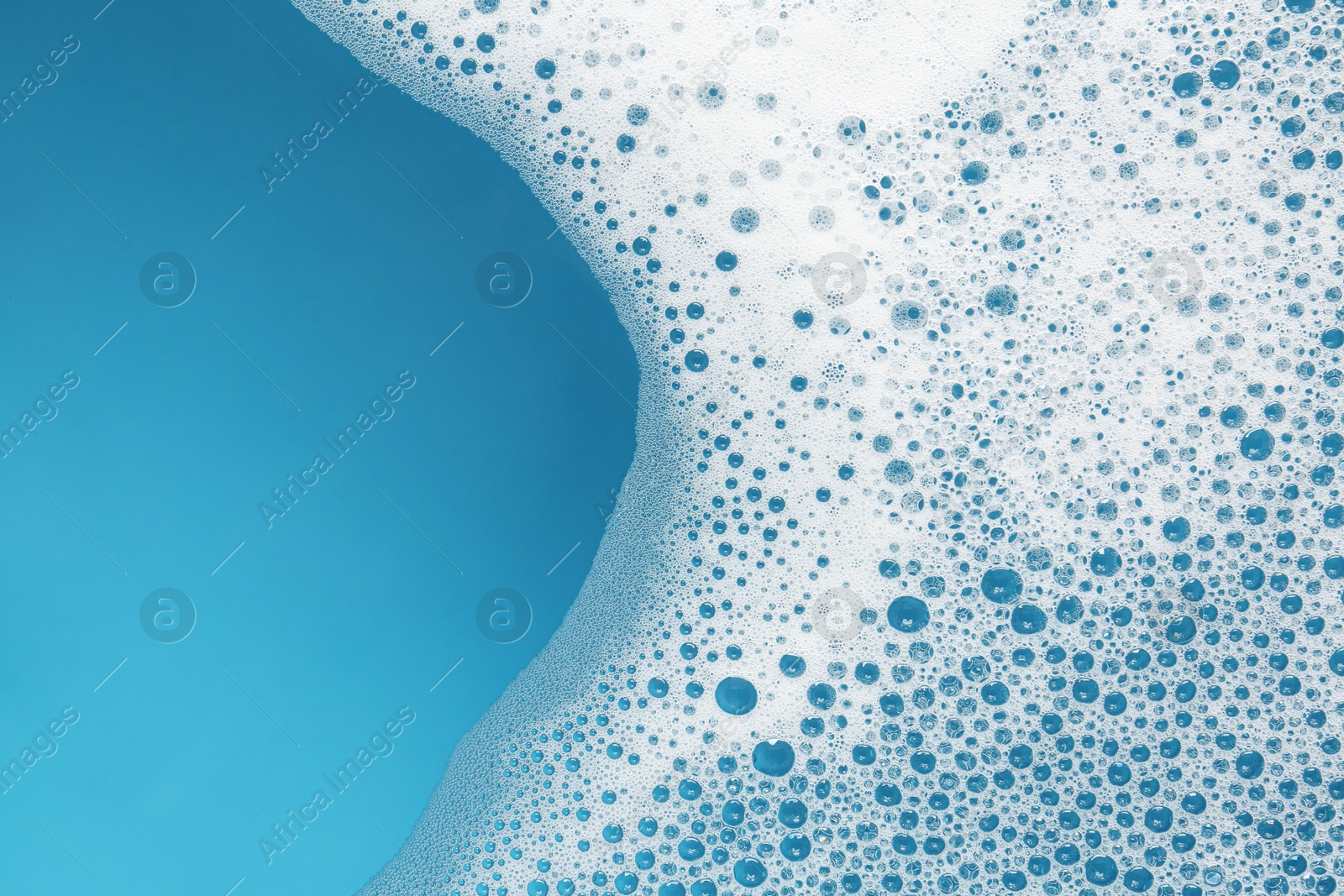 Photo of Detergent foam with bubbles on light blue background, top view. Space for text