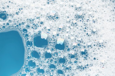 Photo of Detergent foam with bubbles on light blue background, top view