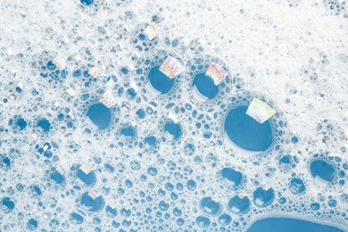 Photo of Detergent foam with bubbles on light blue background, top view