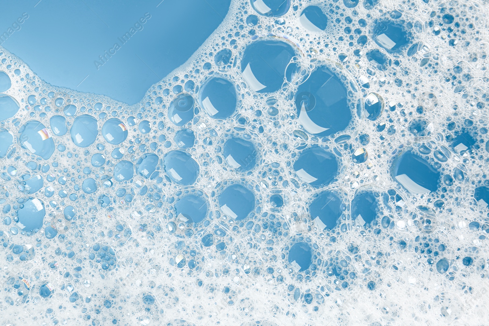 Photo of Detergent foam with bubbles on light blue background, top view