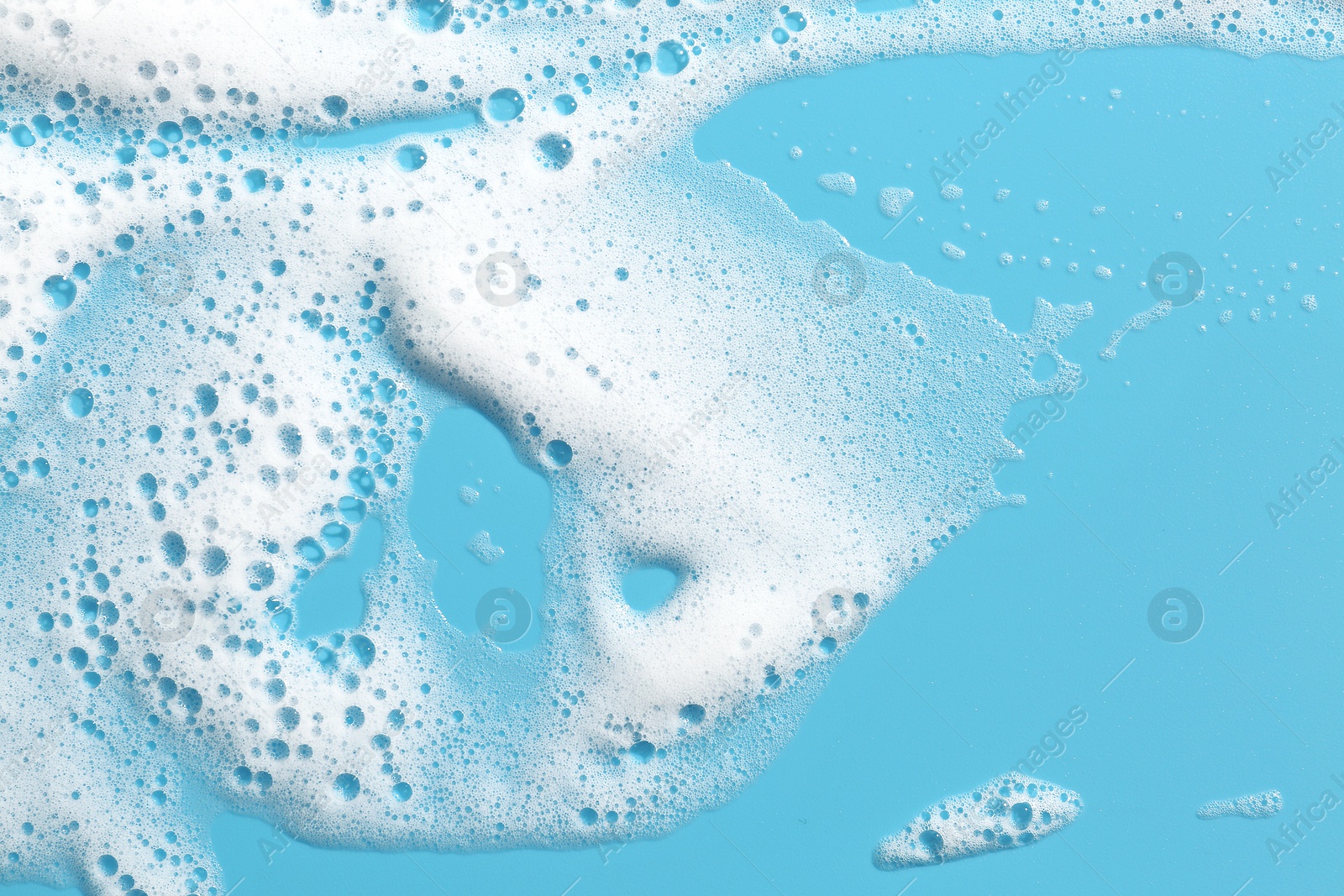 Photo of Detergent foam with bubbles on light blue background, top view