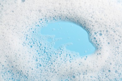 Photo of Detergent foam with bubbles on light blue background, top view