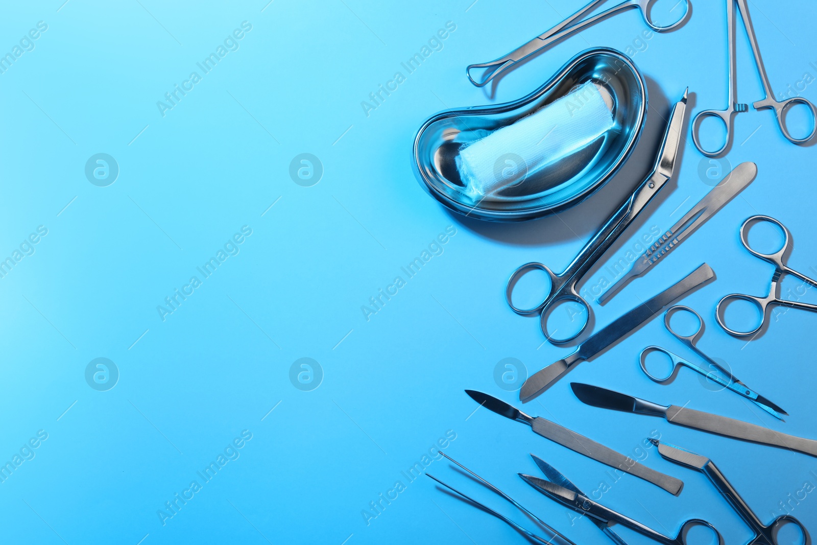 Photo of Different surgical instruments on light blue background, flat lay. Space for text