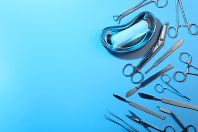 Photo of Different surgical instruments on light blue background, flat lay. Space for text