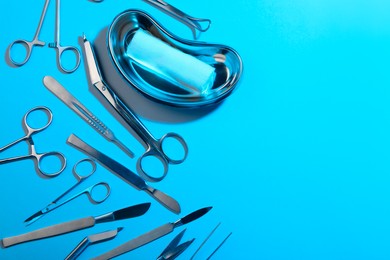 Photo of Different surgical instruments on light blue background, flat lay. Space for text