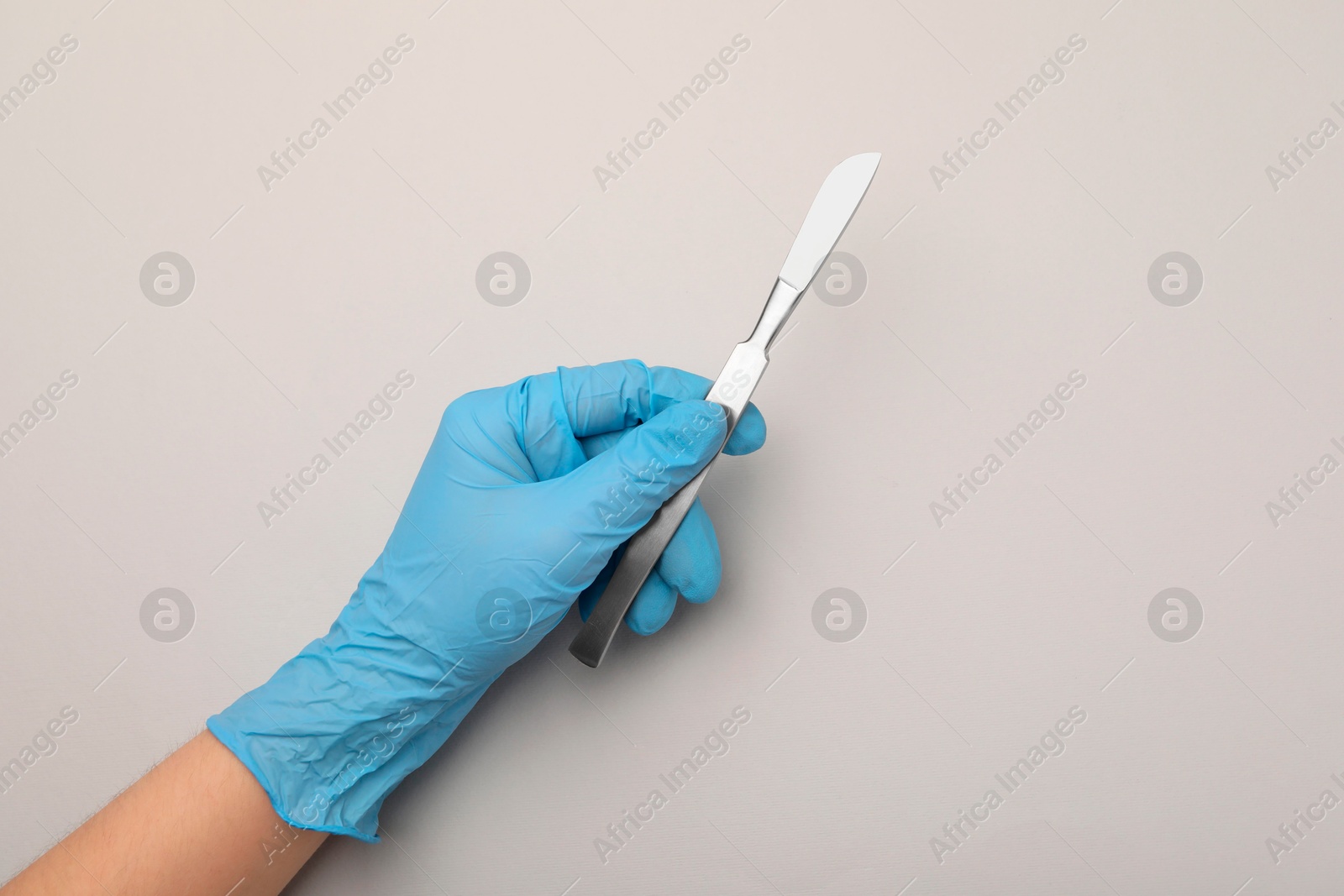 Photo of Doctor with surgical scalpel on light background, top view