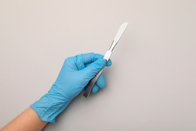 Photo of Doctor with surgical scalpel on light background, top view