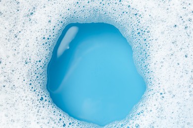 Photo of Detergent foam with bubbles on light blue background, top view