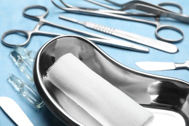 Photo of Different surgical instruments on light blue gauze, closeup