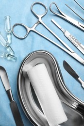 Photo of Different surgical instruments on light blue gauze, flat lay