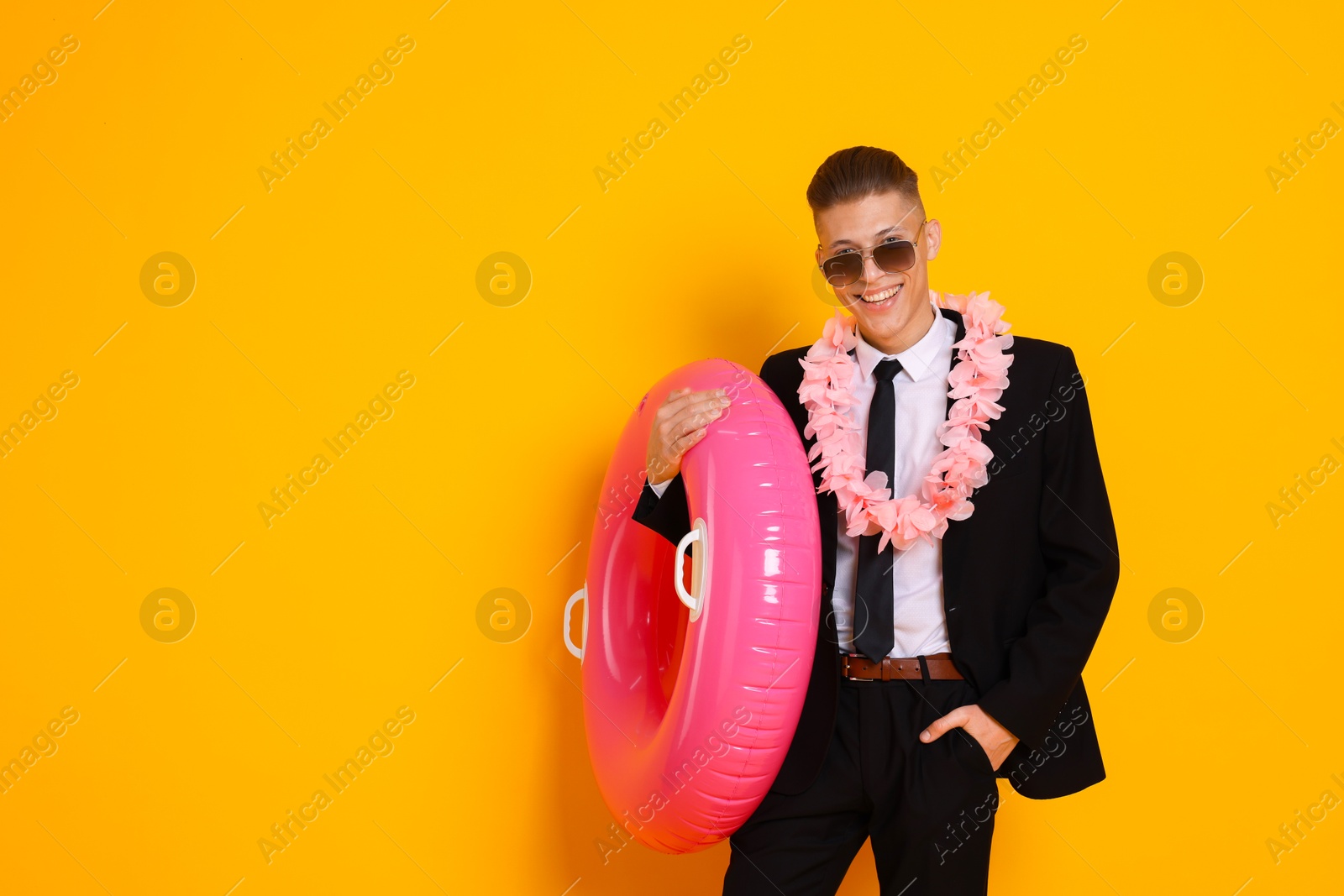 Photo of Businessman with wreath of flowers and inflatable ring on orange background, space for text