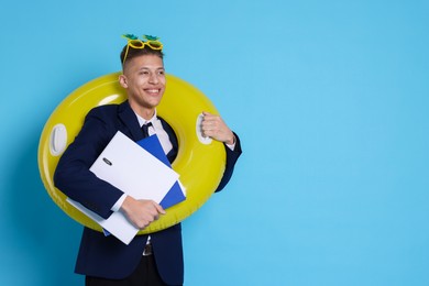 Businessman with inflatable ring, folders and funny sunglasses on light blue background, space for text