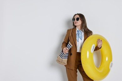 Photo of Businesswoman with inflatable ring, bag and sunglasses on white background, space for text