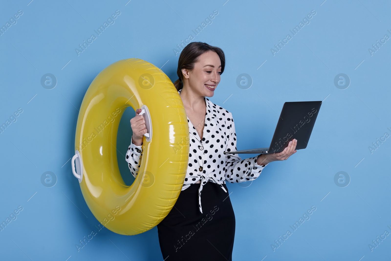 Photo of Businesswoman with inflatable ring and laptop on light blue background