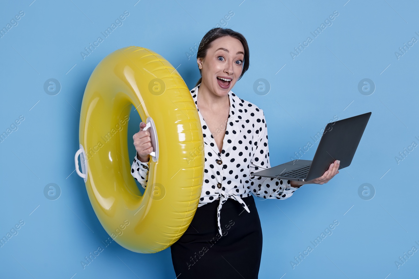 Photo of Surprised businesswoman with inflatable ring and laptop on light blue background