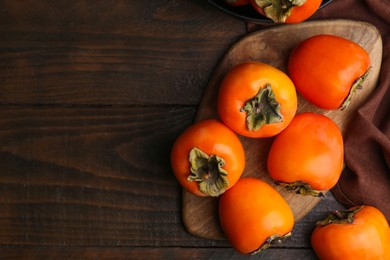 Photo of Delicious ripe juicy persimmons on wooden table, flat lay. Space for text