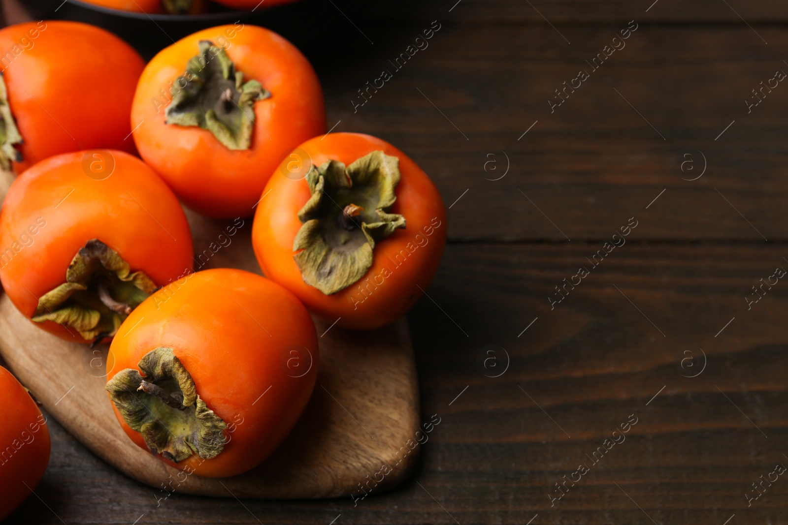 Photo of Delicious fresh juicy persimmons on wooden table, closeup. Space for text