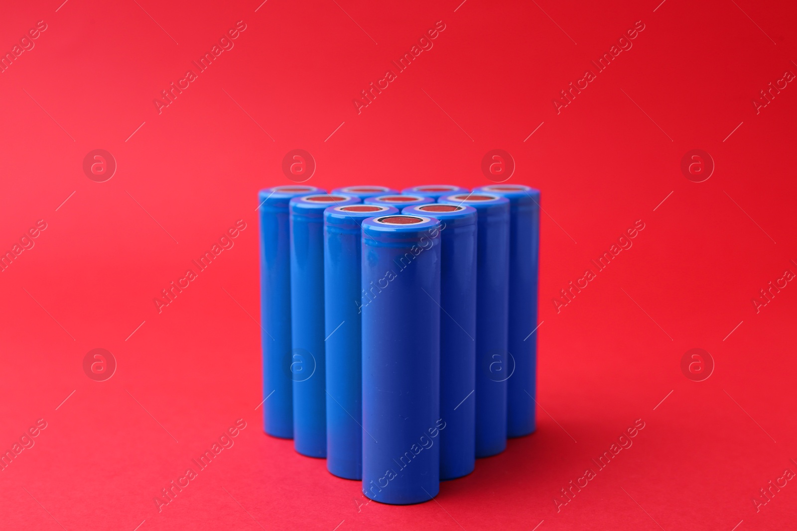 Photo of Many AA cell batteries on red background, closeup